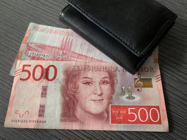 Koyu renk ahşap arka planda siyah deri cüzdanlı İsveç kronu banknotları. İsveç Krona parası - 500 fem hundra kron. 