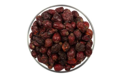 Beyaz arka planda izole edilmiş bir kasede kurumuş gül kalçası manzarası. Sağlıklı beslenme kavramı. Mutfak arka planı.