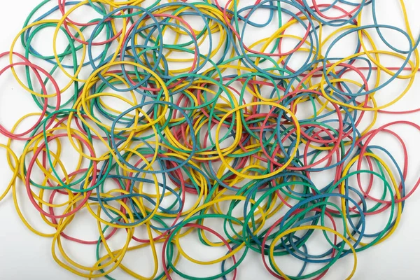Beyaz arkaplanda çok renkli lastik bantların üst görünümü.