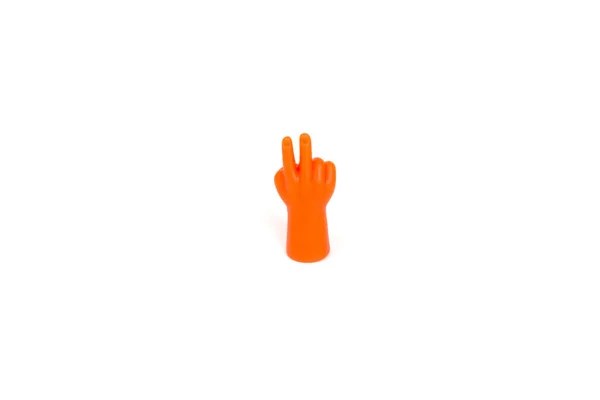 Крупный план изолирован на белом фоне пластиковой оранжевой руки, считая до двух или показывая знак мира. Математика или понятие мира — стоковое фото