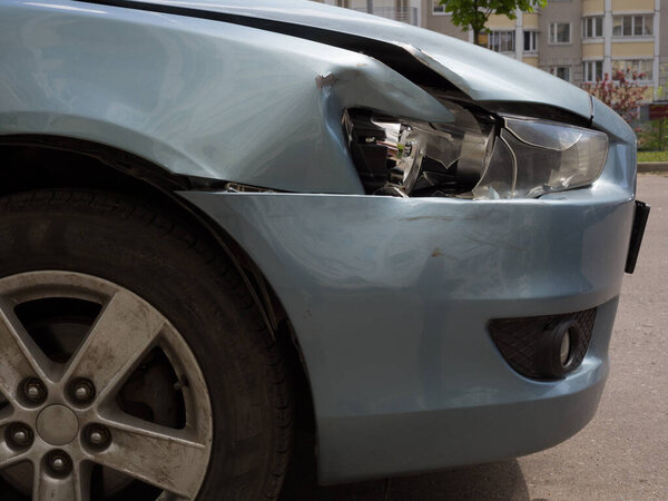 Поврежденное тело седана. Крыло и бампер с вмятиной и сломанной правой фарой автомобиля. 