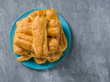 Mavi bir plaka üzerinde gri bir zemin üzerinde Eclairs yığını.