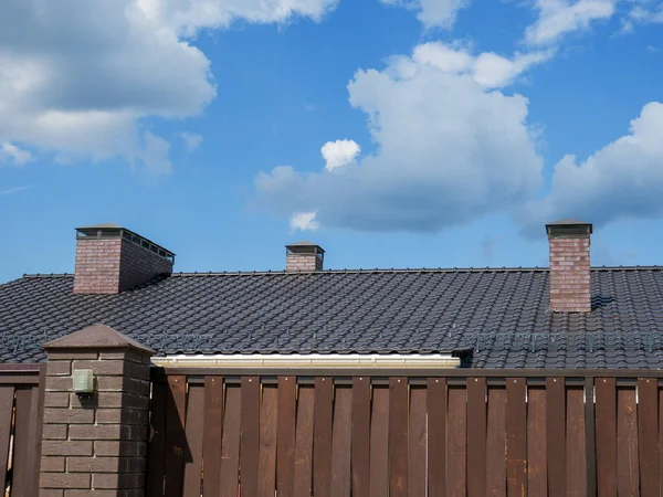 A fragment of a metal-tile roof with three chimneys. — 图库照片