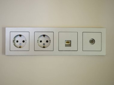Gri dört modül prizinin yakın plan görüntüsü. Çifte elektrik prizi, ethernet soketi ve televizyon soketi..