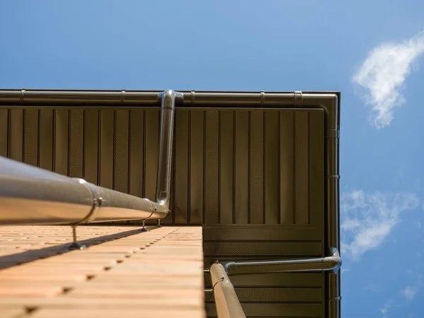 Vista inferior do telhado de uma casa com um ralo de tempestade e o céu azul. Fotografias De Stock Royalty-Free