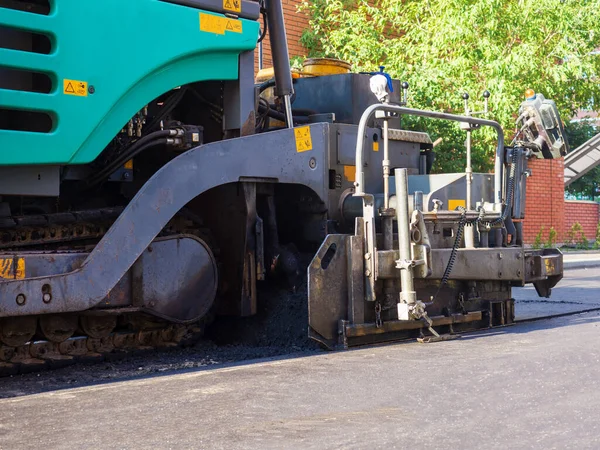 Close-up side view of an road paver in the process of paving asphalt. — Stock Photo, Image