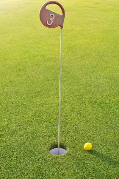 Buraco de golfe com bola amarela — Fotografia de Stock