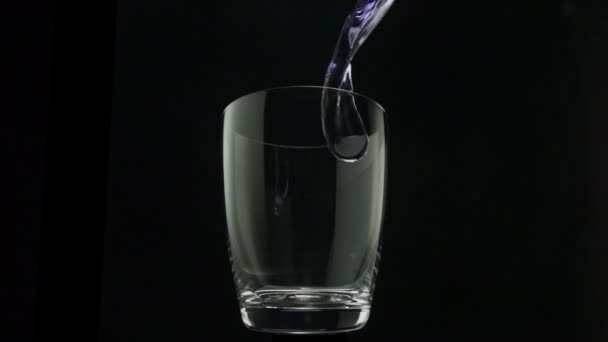 Eau pourpre versant dans le verre 