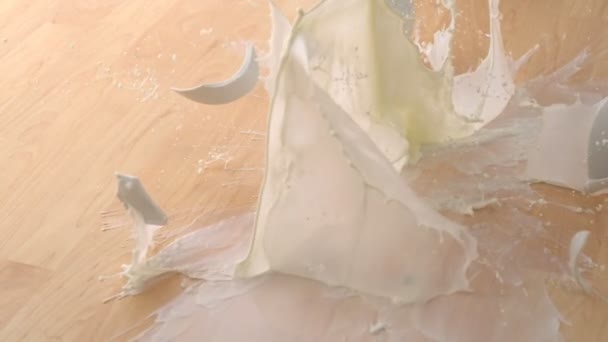 Сбрасывание чашки с молоком и разбивание — стоковое видео