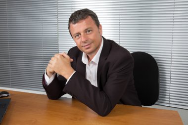 Onun ofisinde çalışırken gülümseyen iş adamı