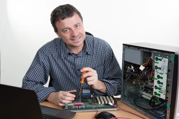 Gelukkig technicus werken aan gebroken computer in zijn kantoor — Stockfoto