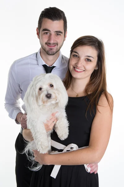 Casal feliz acariciando seu cão branco no sofá em casa na sala de estar — Fotografia de Stock