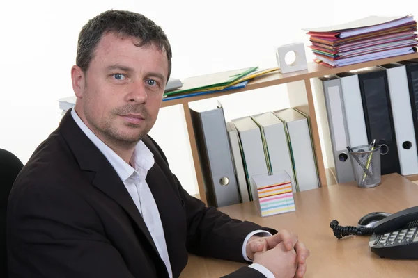 Geschäftsmann mittleren Alters schaut im Büro in die Kamera — Stockfoto