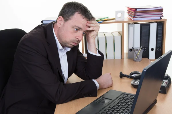 Biznesmen opierając głowę na strony na biurku przed laptopa — Zdjęcie stockowe