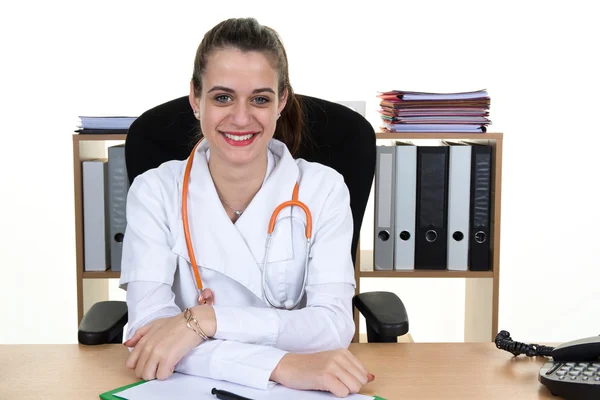 Young smiling doctor sitting at the desk  with arms crossed — Stock Photo, Image