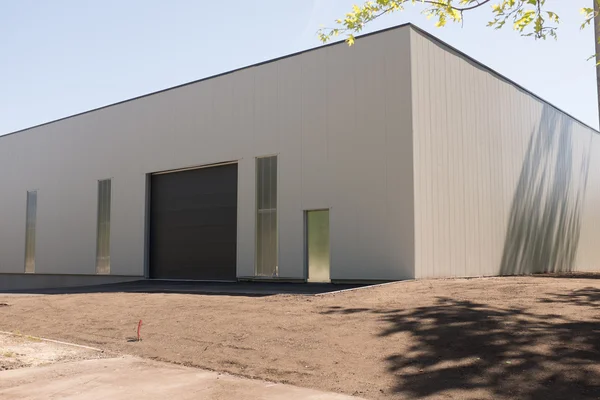 Unidad industrial con puertas enrollables bajo cielo azul y nublado — Foto de Stock