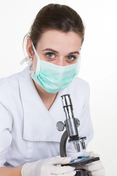 Женщина-врач с помощью микроскопа в лаборатории на белом — стоковое фото
