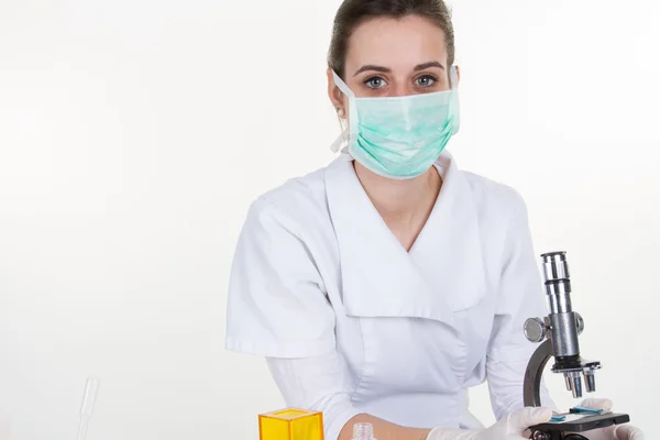 Ärztin oder wissenschaftliche Forscherin in Maske mit Pipette und Mikroskop, Platz für Text. — Stockfoto