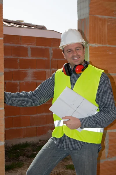 Successful male architect at a building site with blue plan in his arms crossed — Stock Photo, Image