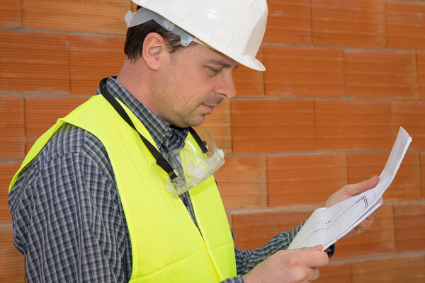 Builder worker with blue print at construction site