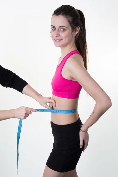 Slim jovem mulher medindo sua cintura fina com uma fita métrica, close-up — Fotografia de Stock