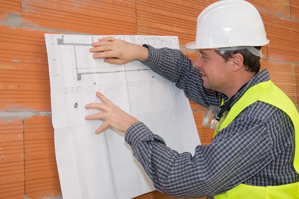 Concept d'architecture et de rénovation résidentielle - architecte homme avec casque et plan Images De Stock Libres De Droits