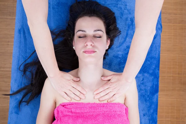 Jovem deitada na mesa de massagem recebendo massagem facial . — Fotografia de Stock