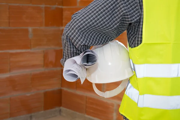 Hand holding a hard hat in front of a concrete wall — Stock Photo, Image