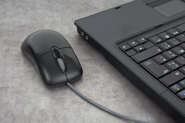 Laptop computer and mouse on a grey desk, top view copy space — Stock Photo, Image