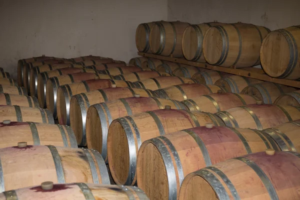 Barris de vinho empilhados na antiga adega da adega. — Fotografia de Stock