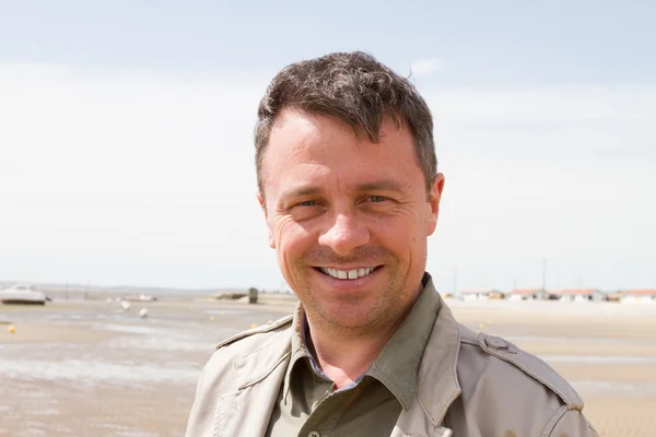 Handsome man smiling at camera at the beach — Stock Photo, Image