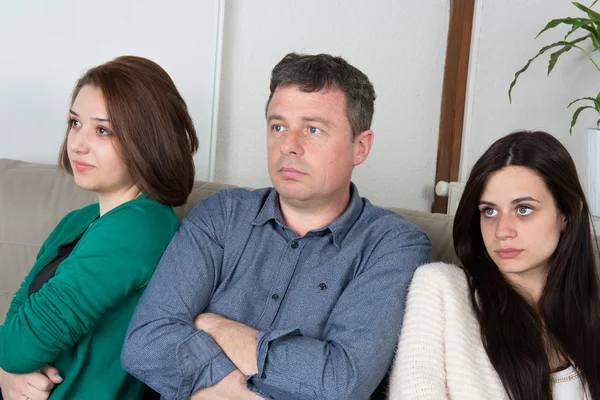 Father reprimending his daughters seated on a sofa — Stock Photo, Image