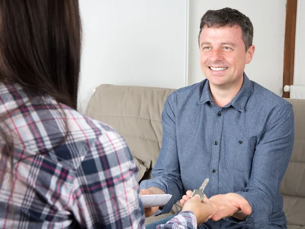 Un homme souriant récupère les clés d'un nouvel appartement après avoir signé des documents — Photo