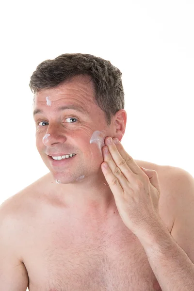Man applying facial cream over white background — Stock Photo, Image