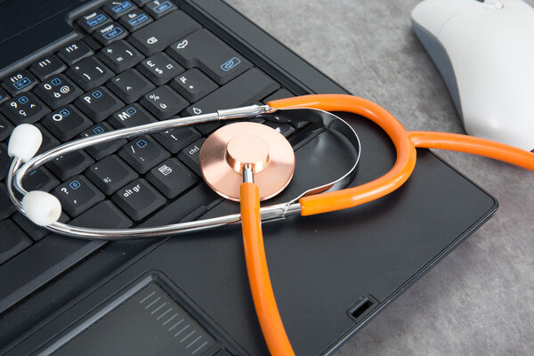 Stethoscopes on laptop keyboard, repair symbol