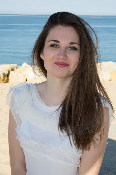 Portret van een mooie brunette met lange haren op het strand. — Stockfoto