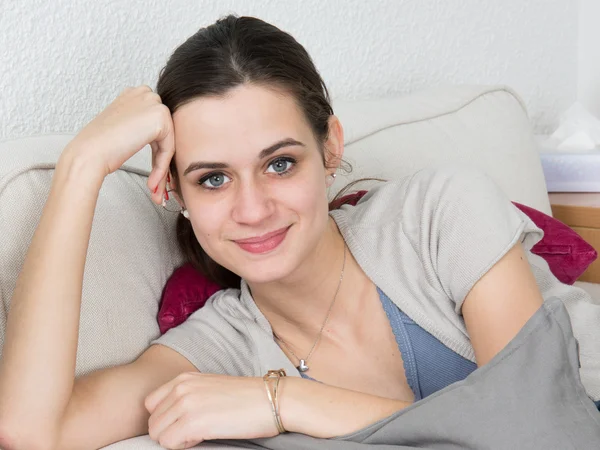 Mujer sonriendo mientras está acostada en un sofá — Foto de Stock