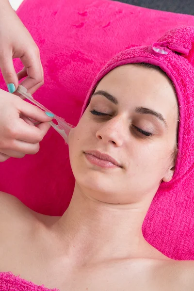 Woman relaxing and removing facial peel off mask on gray. Peeling — Stock Photo, Image