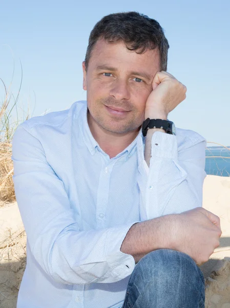 Thoughtful man wearing blue clothes by the sea — Stock Photo, Image