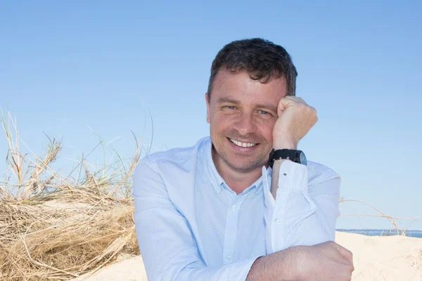 Happy and smiling guy sitting by the sea — Stock Photo, Image