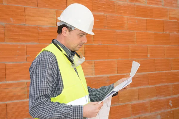 Construction man on the Job site isolated under red bricks — Stock Photo, Image