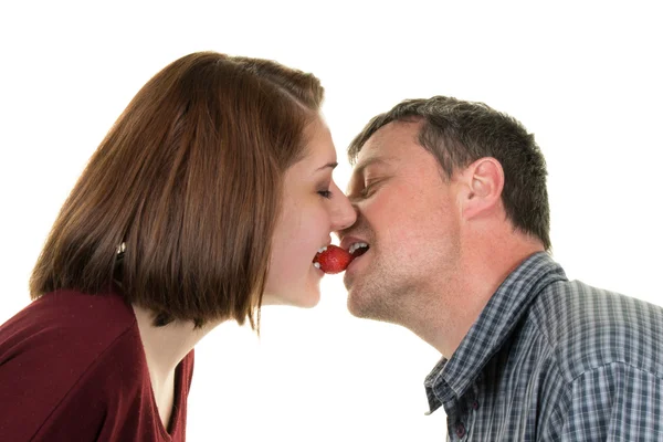 Casal feliz beijando com um morango na boca — Fotografia de Stock