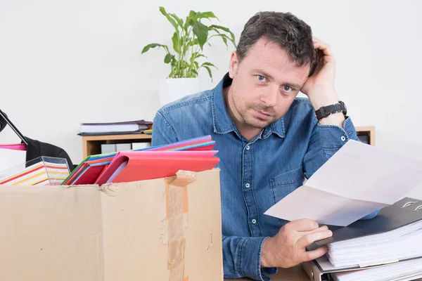Homem triste lendo uma notificação de demissão, preparando sua caixa — Fotografia de Stock
