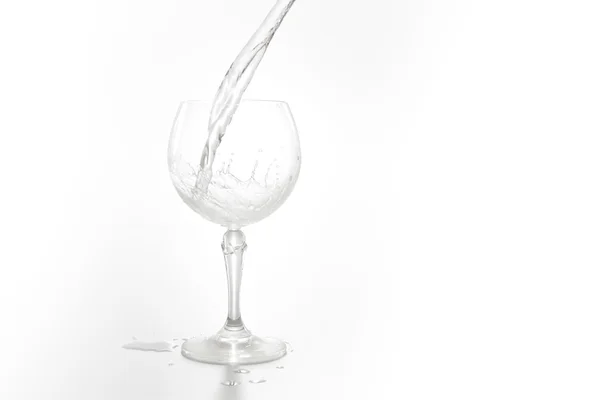 L'acqua scorre in un vino di vetro isolato su bianco — Foto Stock