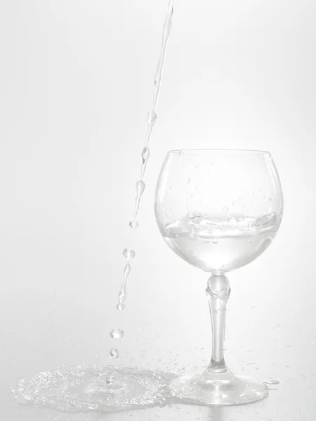 L'acqua fuoriesce dal bicchiere di vino isolato su bianco — Foto Stock