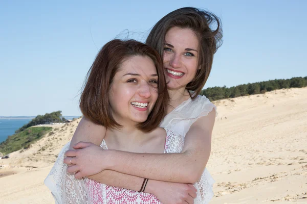 Dos hermanas o amigos en la playa sonriendo a la cámara — Foto de Stock