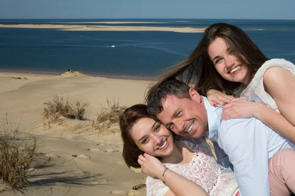 Lächelnde Familie huckepack mit ihrer Tochter am Strand — Stockfoto