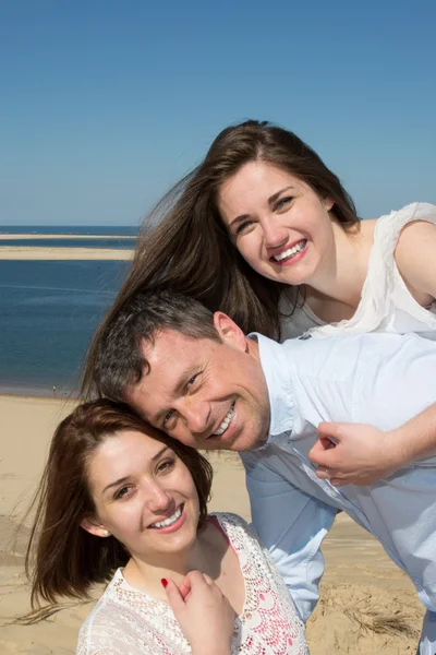 Portrait of a happy family piggybacking their daughter at the beach — Stock Photo, Image