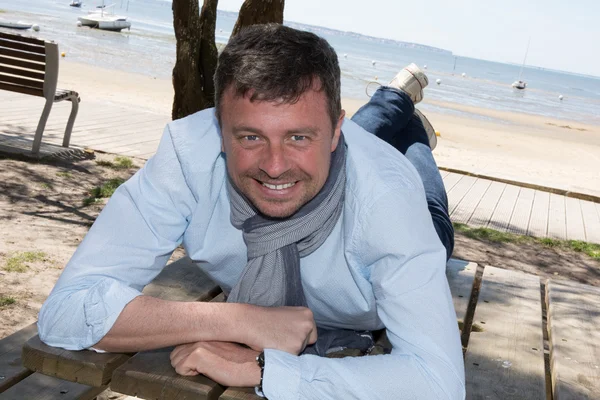 Man lying on wooden table, smiling, portrait — Stock Photo, Image