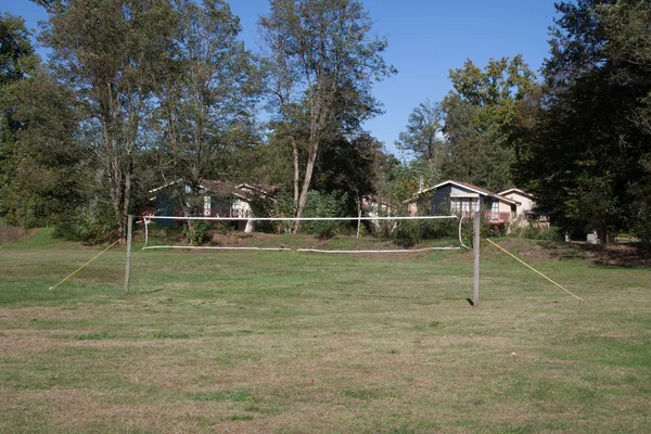 Campo de ténis vazio num jardim sob um céu azul — Fotografia de Stock